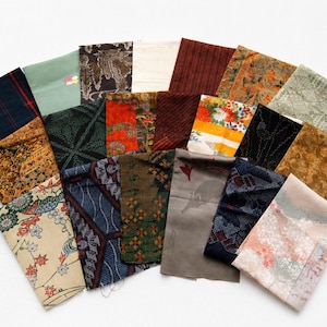Peut inclure: Une collection de vingt et un échantillons de tissu rectangulaires disposés en éventail. Les pièces présentent des motifs variés, notamment floraux, géométriques, à carreaux et abstraits, dans une palette de rouge, vert, bleu, brun, orange et crème.