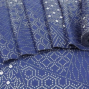 Op de afbeelding: Marineblauwe stof met een wit geometrisch patroon. De stof is opgevouwen en een opgerolde rol is zichtbaar. Het patroon bestaat uit witte stippen en ruitvormen, wat een textuur geeft. Geschikt voor diverse naaiprojecten.