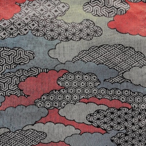 May include: A patterned textile featuring a cloud design in red, gray, blue, and green. The clouds are outlined in black with various geometric patterns. The background has a dotted texture.