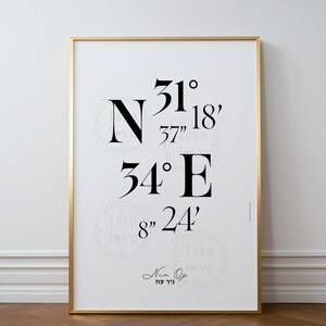 May include: A black and white print with the coordinates 31° 37' 18" N 34° 8" 24' E. The print is framed in a gold frame and has a white background.