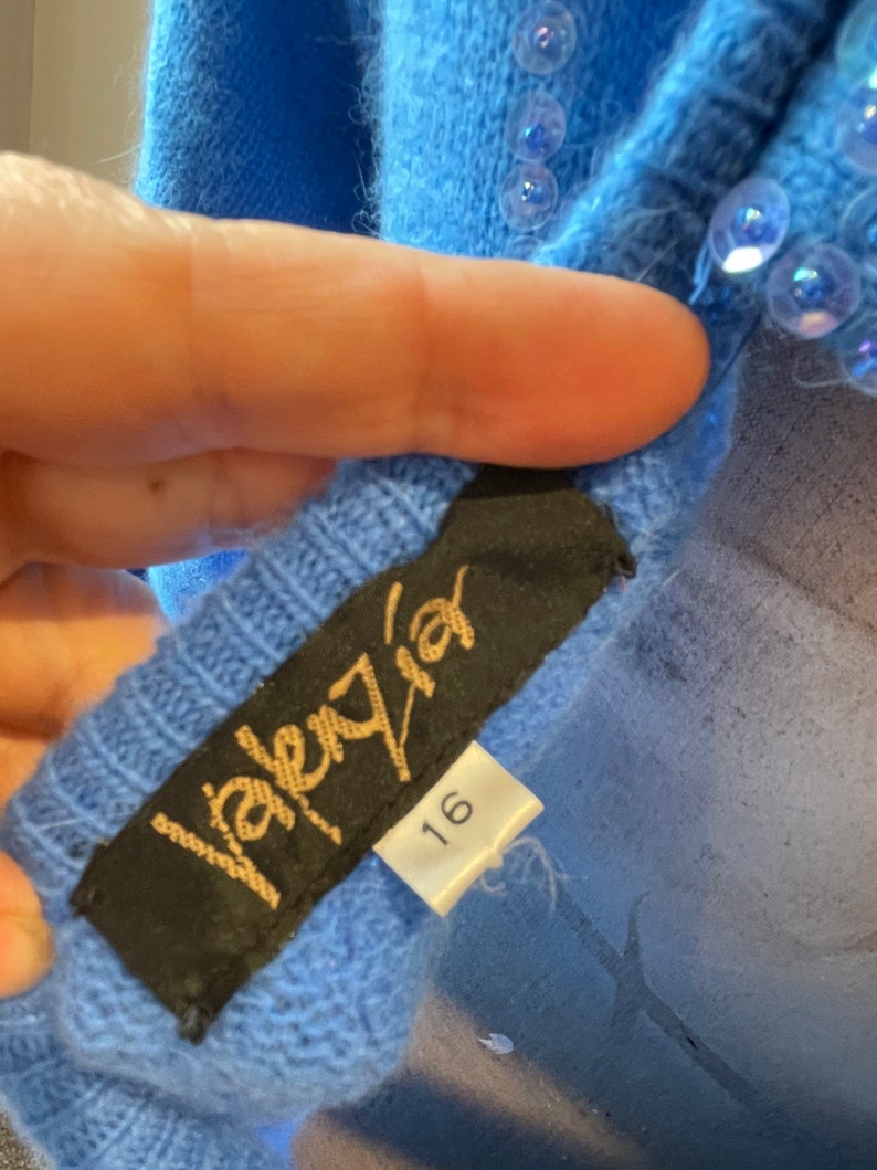 May include: A blue sweater with sequins and a black label that says "Valery" and "16".