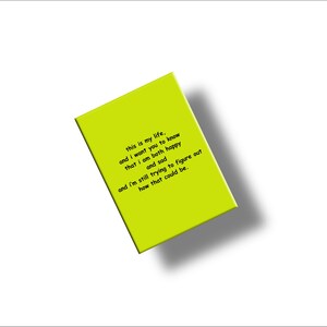 May include: A bright chartreuse-colored rectangular object with the text "this is my life, and I want you to know that I am both happy and sad and I'm still trying to figure out how that could be." The object is angled on a white background.