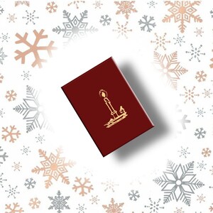 May include: A burgundy box with a gold candle design. The box is rectangular and has a glossy finish. The background features a pattern of snowflakes in silver and rose gold.