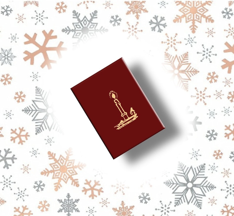 May include: A burgundy box with a gold candle design. The box is rectangular and has a glossy finish. The background features a pattern of snowflakes in silver and rose gold.