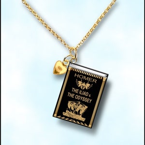 May include: A gold necklace with a black book charm that says "HOMER THE ILIAD & THE ODYSSEY". The charm has a gold heart attached to it.