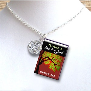 May include: A silver necklace with a tree charm and a miniature book charm. The book cover is red with a black silhouette of a tree and the text "To Kill a Mockingbird" by Harper Lee.