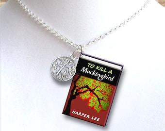 May include: A silver necklace with a tree charm and a miniature book charm. The book cover is red with a black silhouette of a tree and the text "To Kill a Mockingbird" by Harper Lee.