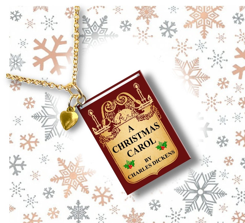 May include: Gold-toned necklace with a small heart charm and a pendant shaped like a book. The book pendant is burgundy with gold lettering and the title "A Christmas Carol" by Charles Dickens.