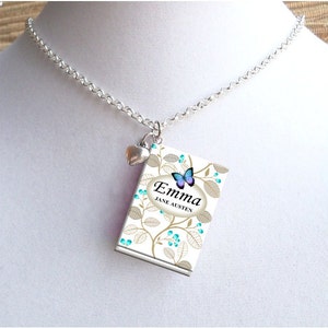 May include: A silver chain necklace with a charm featuring a book cover with a butterfly and the title "Emma" by Jane Austen. The charm also has a small silver heart.