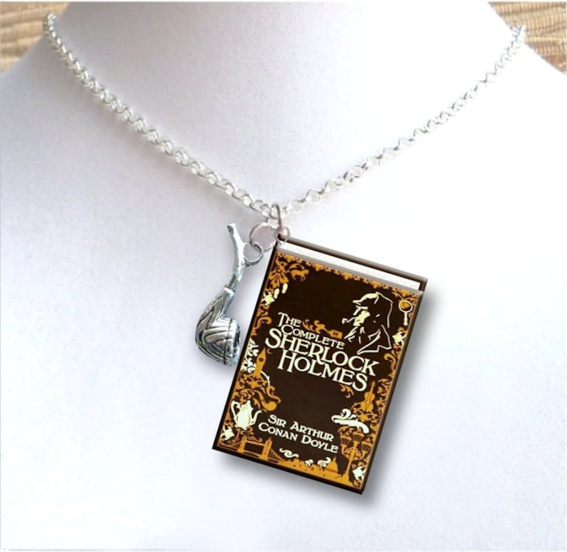 May include: A silver chain necklace with a charm of a book titled "The Complete Sherlock Holmes" by Sir Arthur Conan Doyle and a silver pipe charm.