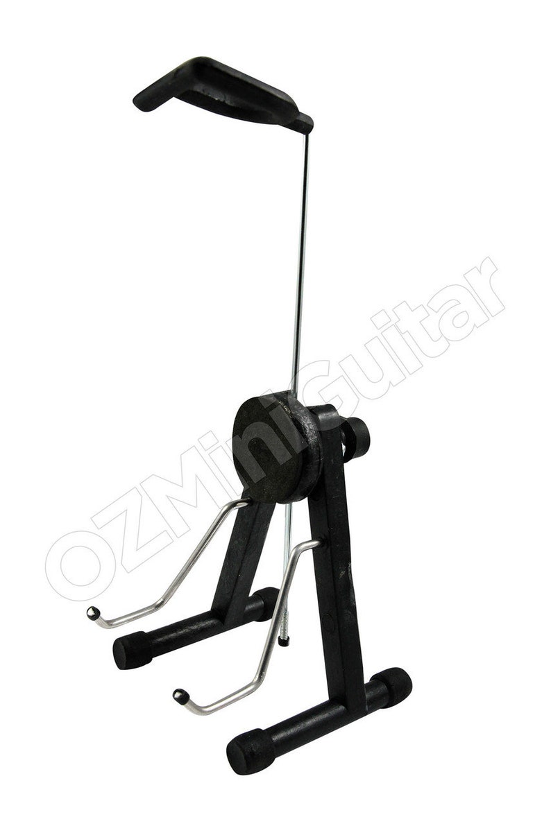 May include: Black guitar stand with a curved top and adjustable height. The stand has a black base and support arms with rubber ends to hold the guitar. The stand is designed to hold a guitar upright.