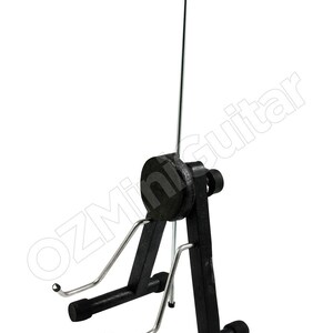 May include: Black guitar stand with a curved top and adjustable support. The stand has a black base and frame with silver-colored supports for the guitar. The stand is designed to hold a guitar upright.
