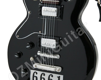 May include: A black electric guitar with silver components and a white trim. The guitar features the number "6661" on a white label. It is mounted on a black stand.