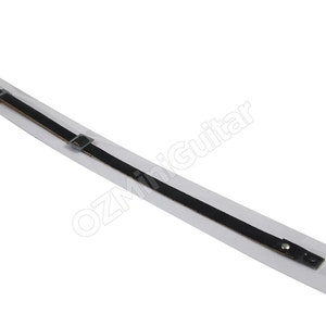 May include: A long, thin black strap with a metallic buckle and a silver-toned stud fastener at one end. The strap is mounted on a rectangular white backing card that features the text OZMiniGuitar printed in a light gray, slanted font.