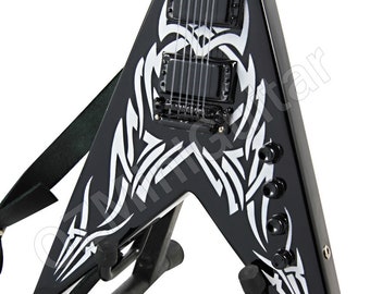 May include: Black V-shaped electric guitar with white tribal design. The guitar has a black strap and is mounted on a black stand. Features include black tuning knobs and pickups.