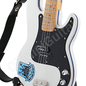 May include: A white electric guitar with a black pickguard and a West Ham United FC logo. The guitar has a black strap and is mounted on a black stand. The body is outlined with blue trim.