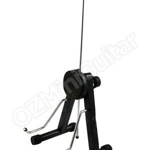 May include: A black and silver metal guitar stand featuring a vertical support arm with a top cradle, a central circular adjustment knob, and two lower support arms with protective tips. The text OZMiniGuitar is visible across the frame.