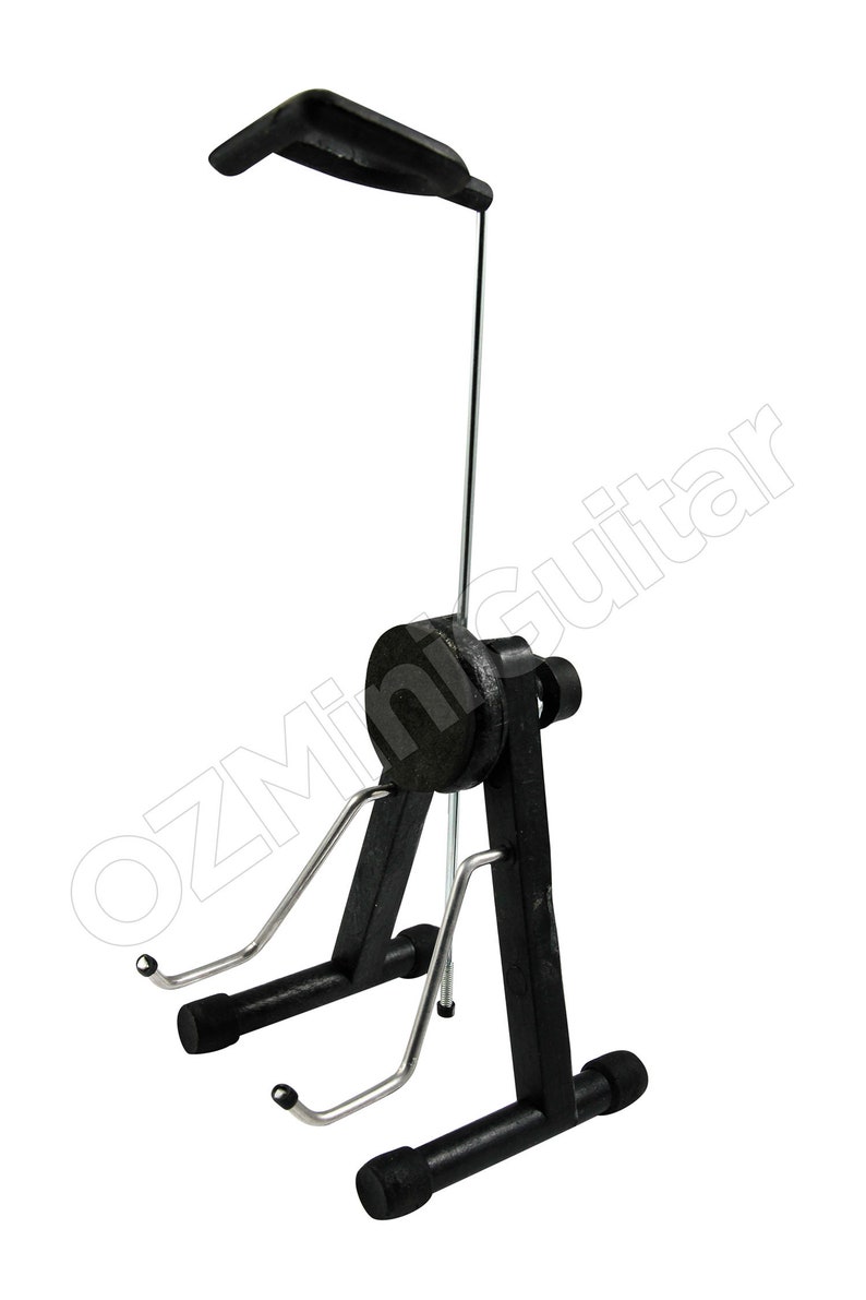 May include: A black and silver metal guitar stand featuring a vertical support arm with a top cradle, a central circular adjustment knob, and two lower support arms with protective tips. The text OZMiniGuitar is visible across the frame.