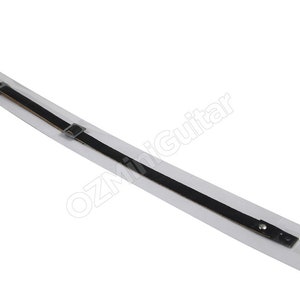 May include: A black guitar strap with a silver buckle and rivets, packaged in a clear plastic sleeve. The strap is made of a thin, durable material and is designed to be worn over the shoulder.