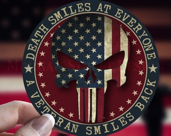 Op de afbeelding: Een ronde sticker met een blauwe rand en een rode achtergrond. De sticker heeft een schedel met een witte omtrek en een Amerikaans vlagontwerp. De tekst "Death Smiles At Everyone A Veteran Smiles Back" staat rond de schedel.