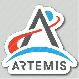 May include: A sticker featuring the word "ARTEMIS" in gray, with a stylized "A" above it. The "A" is composed of a gray triangle and a white triangle. Red and blue curved lines and a blue circle complete the design.