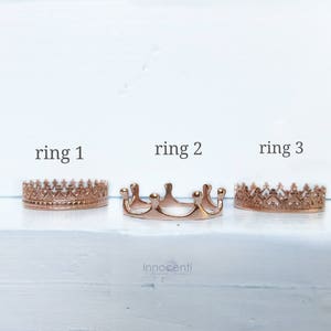 May include: Three rose gold crown rings are presented on a white surface. Each ring features a distinct design, with the text "ring 1", "ring 2", and "ring 3" above them. These rings are likely intended for adornment or as jewellery.