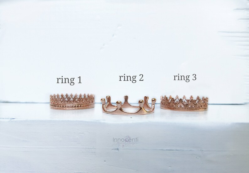 May include: Three rose gold crown rings are presented on a white surface. Each ring features a distinct design, with the text "ring 1", "ring 2", and "ring 3" above them. These rings are likely intended for adornment or as jewellery.