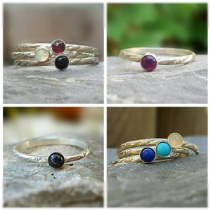 Puede incluir: Anillos de plata con diferentes piedras preciosas. Los anillos presentan piedras redondas en colores como &oacute;palo, rub&iacute;, negro, azul y turquesa. Los anillos tienen un dise&ntilde;o de banda texturizada. La marca "Innocenti" es visible.