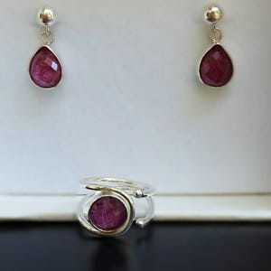 K&ouml;nnte beinhalten: Ein Paar silberne Ohrringe mit einem tropfenf&ouml;rmigen rosa Stein und ein silberner Ring mit einem runden rosa Stein.