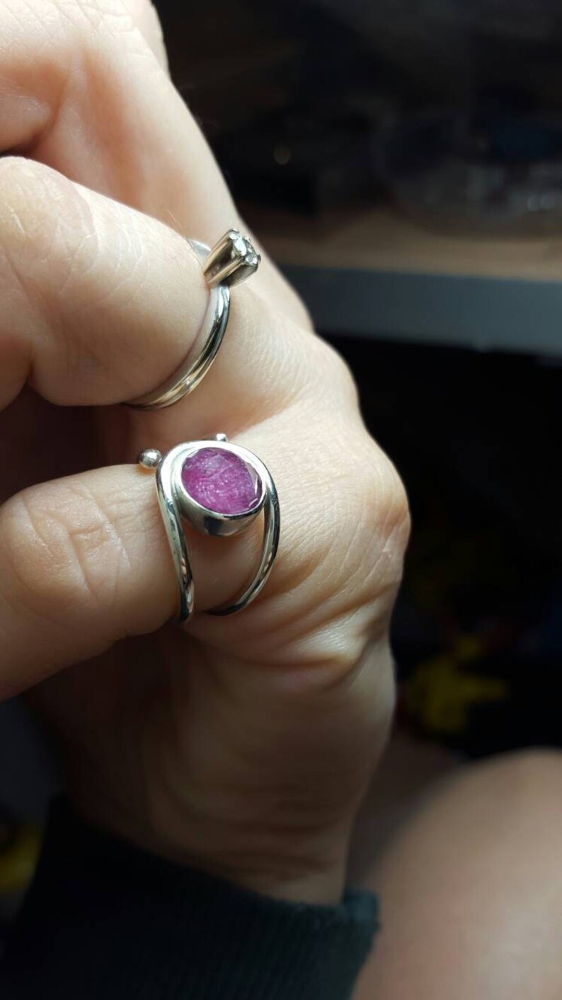 K&ouml;nnte beinhalten: Zwei Silberringe mit Edelsteinen. Der Ring links hat einen kleinen, klaren Edelstein. Der Ring rechts hat einen gr&ouml;&szlig;eren, rosafarbenen Edelstein.