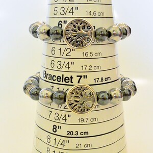 K&ouml;nnte beinhalten: Drei Armb&auml;nder mit schwarzen und silbernen Perlen und einem silbernen Lebensbaum-Anh&auml;nger. Die Armb&auml;nder werden auf einem Ma&szlig;band mit den folgenden Gr&ouml;&szlig;en angezeigt: 15,2 cm, 17,8 cm und 20,3 cm.