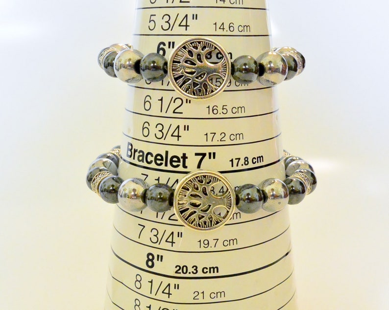 K&ouml;nnte beinhalten: Drei Armb&auml;nder mit schwarzen und silbernen Perlen und einem silbernen Lebensbaum-Anh&auml;nger. Die Armb&auml;nder werden auf einem Ma&szlig;band mit den folgenden Gr&ouml;&szlig;en angezeigt: 15,2 cm, 17,8 cm und 20,3 cm.