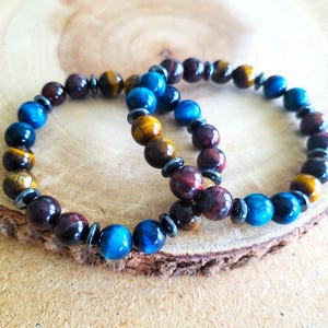 May include: Two beaded bracelets with tiger's eye, red jasper, and blue tiger's eye stones. The bracelets are separated but are lying on top of each other.