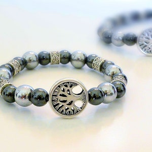 May include: A silver bracelet with a tree of life charm and black and silver beads.
