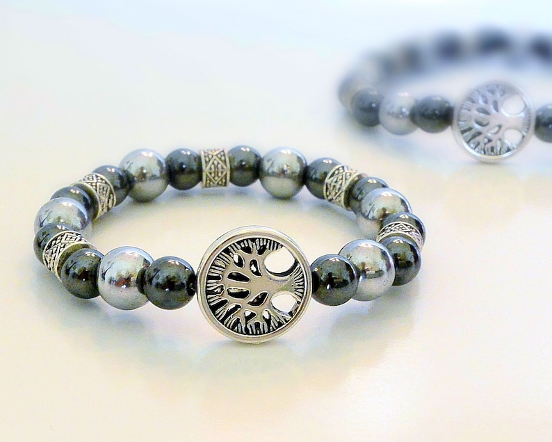 K&ouml;nnte beinhalten: Ein silbernes Armband mit einem Lebensbaum-Anh&auml;nger und schwarzen und silbernen Perlen.
