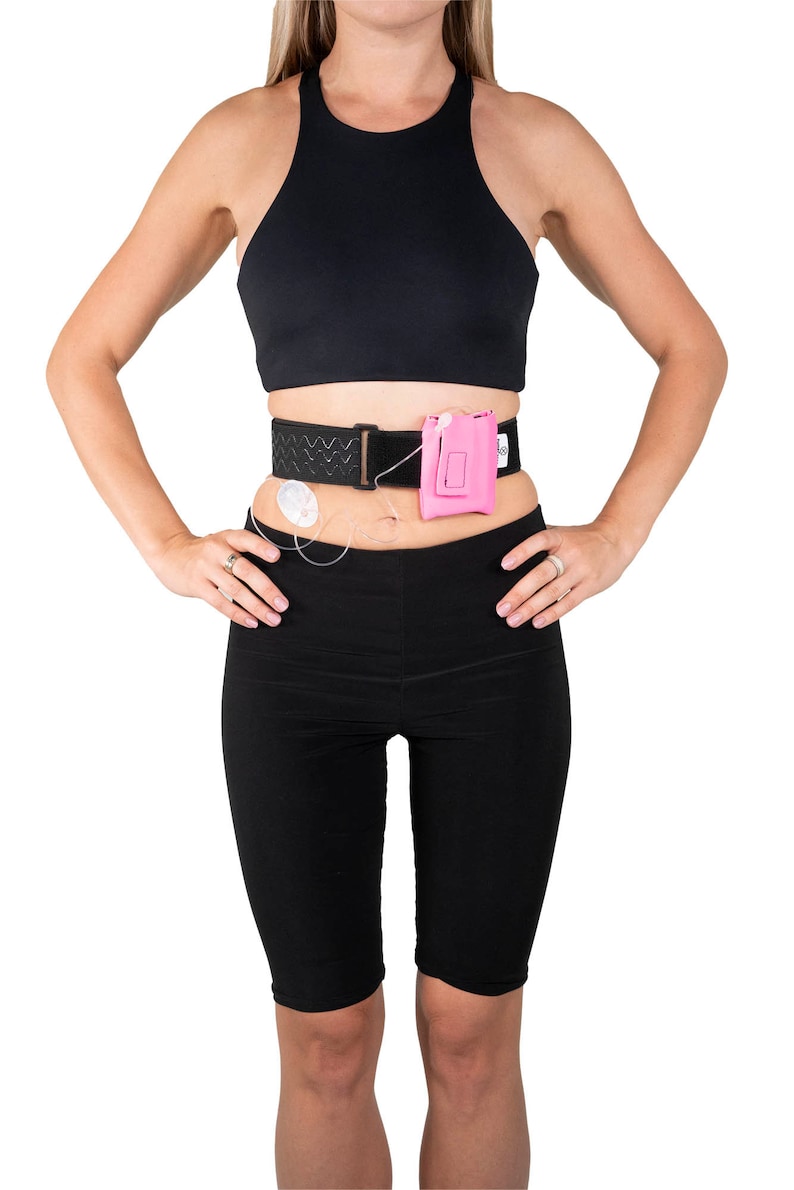 A model, whose belly button and lower rib cage are exposed, is wearing a Pumpcases™ hot pink, adjustable, insulin pump waist belt, compatible with t:slim X2 made for Diabetics. This belt is placed above her belly button.