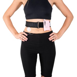 A model, whose belly button and lower rib cage are exposed, is wearing a Pumpcases™ rose pink, adjustable, insulin pump waist belt, compatible with t:slim X2 made for Diabetics. This belt is placed above her belly button.