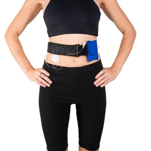 A model, whose belly button and lower rib cage are exposed, is wearing a Pumpcases™ royal blue, adjustable, insulin pump waist belt, compatible with t:slim X2 made for Diabetics. This belt is placed above her belly button.
