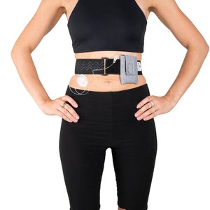 A model, whose belly button and lower rib cage are exposed, is wearing a Pumpcases™ heather gray, adjustable, insulin pump waist belt, compatible with t:slim X2 made for Diabetics. This belt is placed above her belly button.