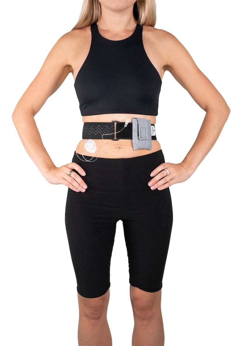 A model, whose belly button and lower rib cage are exposed, is wearing a Pumpcases™ heather gray, adjustable, insulin pump waist belt, compatible with t:slim X2 made for Diabetics. This belt is placed above her belly button.
