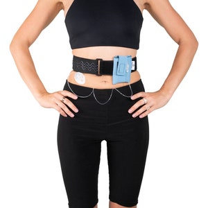 A model, whose belly button and lower rib cage are exposed, is wearing a Pumpcases™ sky blue, adjustable, insulin pump waist belt, compatible with t:slim X2 made for Diabetics. This belt is placed above her belly button.