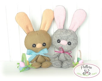 May include: Two felt Easter bunny plush toys, one brown with a blue and white checkered bow and a green basket, and one gray with a pink bow and a green basket. The text "Pattern Little Things to Share" is on a white oval.
