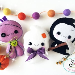 May include: Three felt Halloween character ornaments: a purple stitched monster, a white ghost with a purple bow, and a black grim reaper with a brown scythe. The ornaments are on a white background with a garland of colorful felt balls.