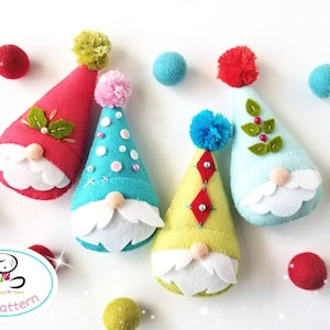 Könnte beinhalten: Vier Filz-Gnom-Ornamente mit verschiedenen farbigen Hüten und Verzierungen. Die Gnome tragen weiße Filzbärte und haben rote, blaue, grüne und gelbe Hüte. Die Hüte sind mit Filzblättern, Bommeln und Perlen verziert. Die Gnome sitzen auf einer weißen Oberfläche.  PDF-Muster.
