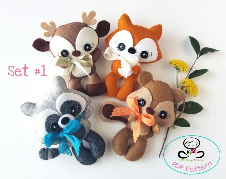 Pu&ograve; includere: Set di quattro giocattoli di peluche in feltro, tra cui un cervo, una volpe, un procione e uno scoiattolo. I giocattoli sono di colore marrone, arancione, grigio e marrone con accenti bianchi. I giocattoli hanno occhi a bottone neri e tengono dei fiocchi. Il testo "Set #1" &egrave; nell'angolo in alto a sinistra dell'immagine. Il testo "Little Things to Share PDF Pattern" &egrave; nell'angolo in basso a destra dell'immagine.