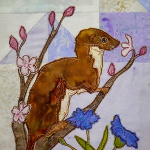 May include: A brown weasel with a white chest sits on a branch with pink blossoms. The weasel is looking to the right. Two blue flowers with green stems are below the branch.