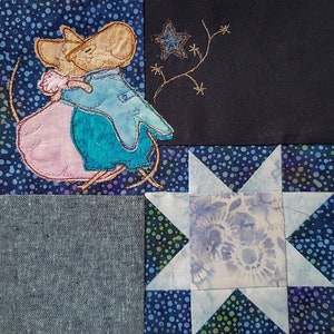 Könnte beinhalten: Eine blaue und rosa gestickte Maus mit einem Stern- und Rankendesign auf einem blauen und weißen Stoffhintergrund.