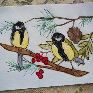 May include: Two embroidered birds perched on a branch with red berries. The birds are yellow with black markings and are surrounded by green foliage.