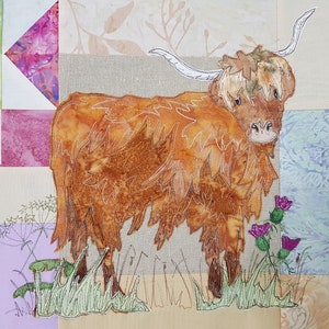 Op de afbeelding: Een bruine en witte Highland koe met lange, ruwe vacht staat in een veld met groen gras. De koe is geborduurd op een patchwork deken met verschillende gekleurde stoffen.