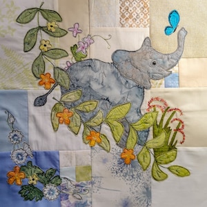 May include: A patchwork quilt with a blue elephant design, surrounded by green and yellow floral embroidery. A blue butterfly is flying above the elephant's trunk.